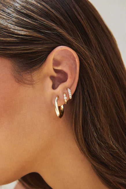 Close up of EF-Collection Diamond Zoe Huggie Earrings in yellow gold styled on models ear