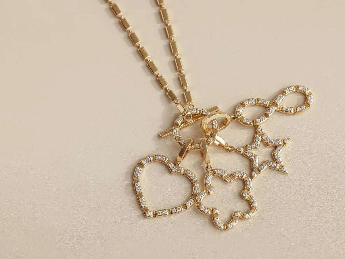Onirikka Glimmer Diamond Infinity Charm in 18k yellow gold with diamonds a beige background with other charms