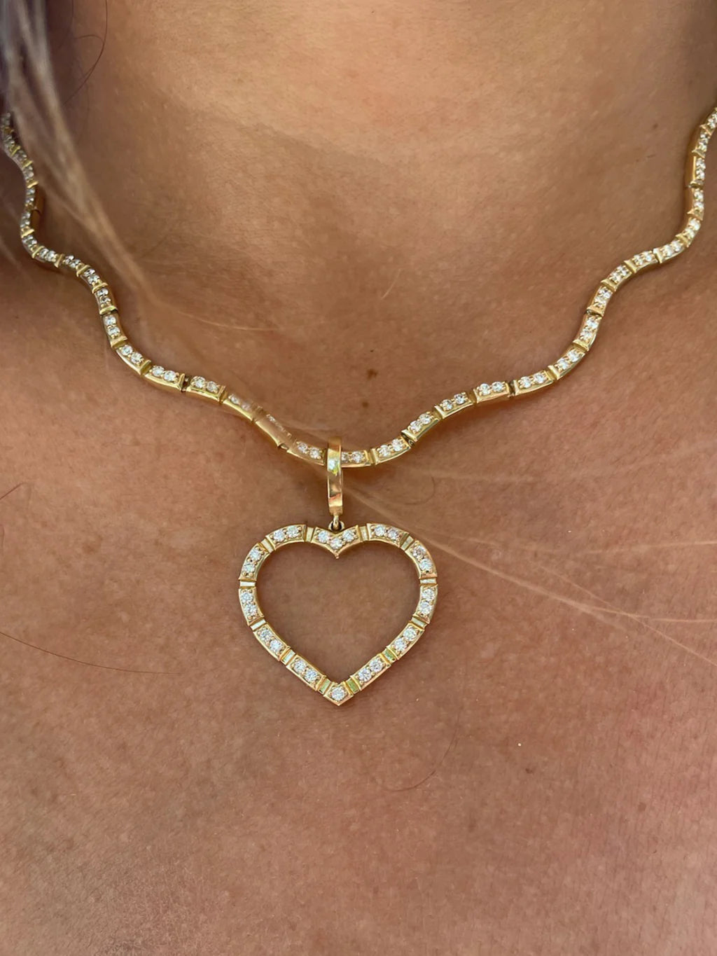 close up of Onirikka Glimmer Wave tennis Necklace in yellow gold with a charm