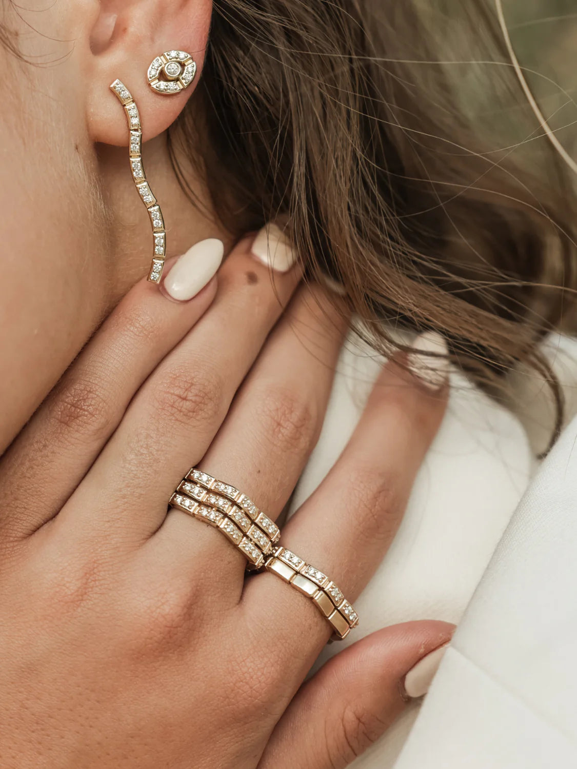 close up of Onirikka Glimmer Wave Diamond Ring in 18k yellow gold styled with different rings on a model's hand.
