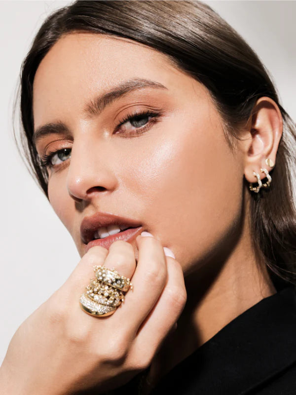 Close-up of a woman wearing Onirikka full Pave Floret Hoop, yellow gold jewelry.