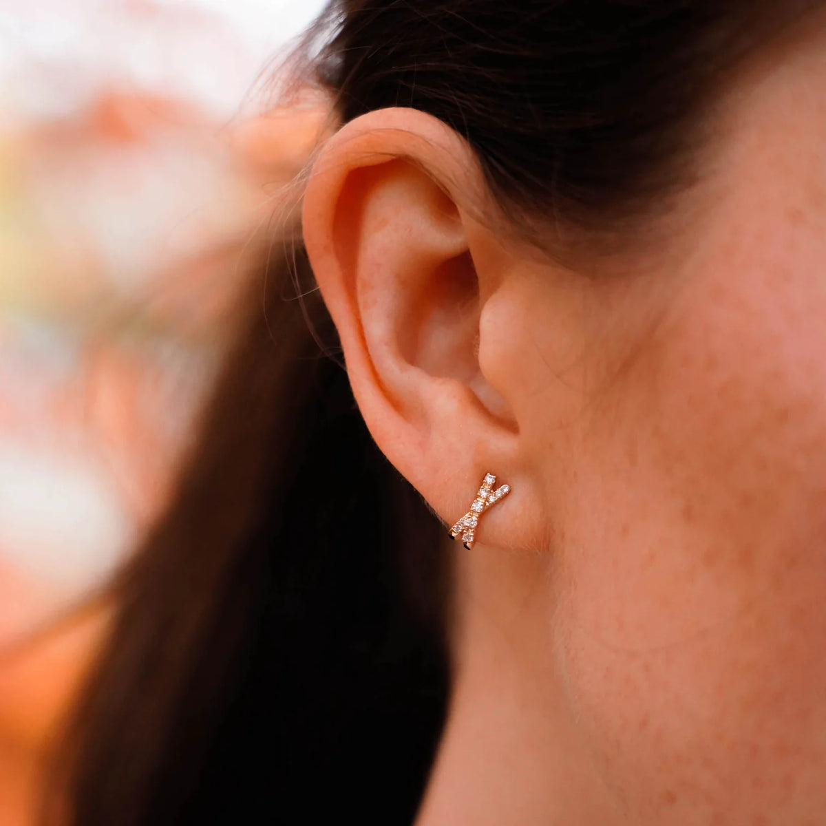 Single Dana Rebecca Designs Ava Bea Crossover Mini Huggie Earrings in rose gold on models ear