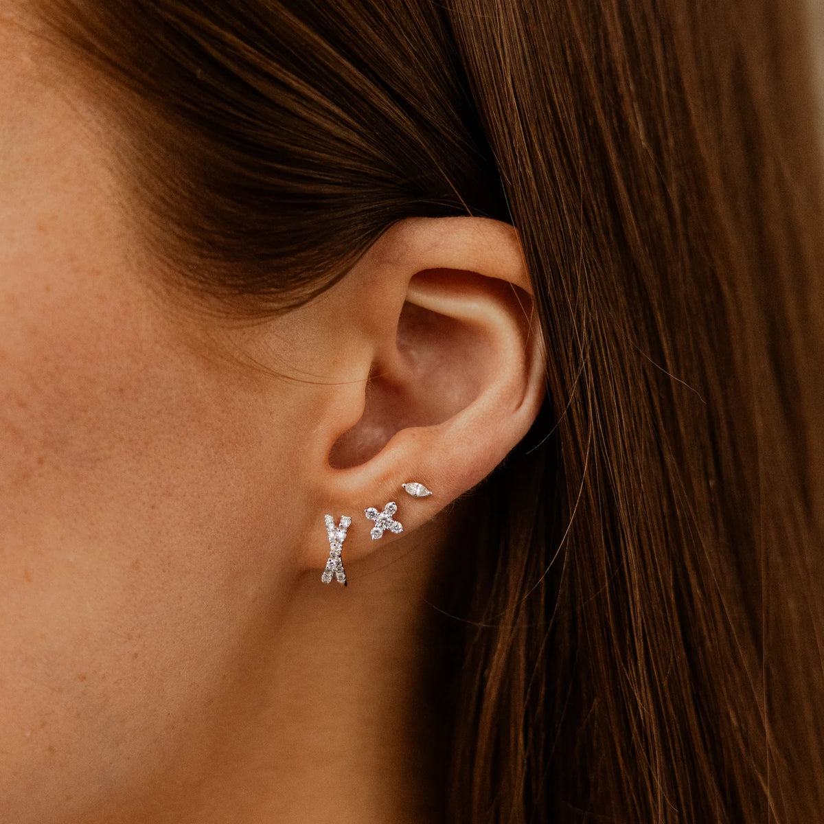 Dana Rebecca Designs Ava Bea Crossover Mini Huggie Earrings in white gold stacked on models ear