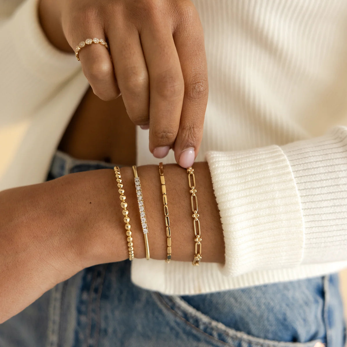 Dana Rebecca Designs Ava Bea Flexi Cuff Bracelet in yellow gold styled on models wrist wearing a white sweater