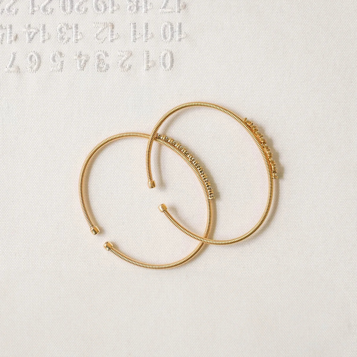 Two Dana Rebecca Designs Ava Bea Flexi Cuff Bracelet in yellow gold on white cloth background
