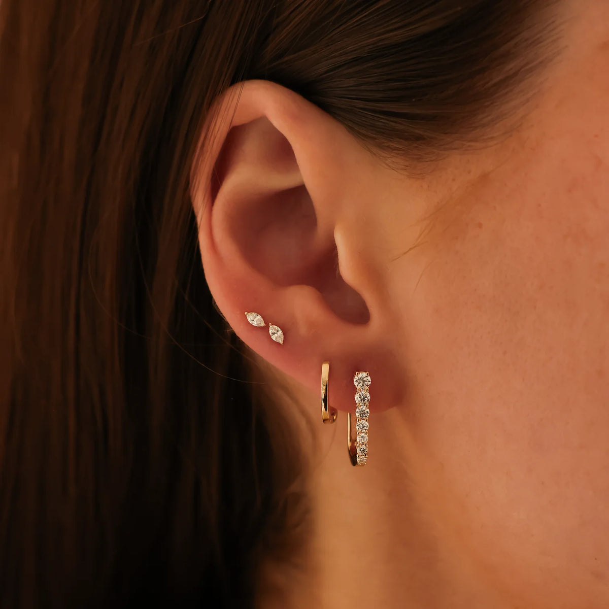 Dana Rebecca Designs Ava Bea Graduating U Hoops in yellow gold stacked on models ear with marquise studs and yellow gold huggie