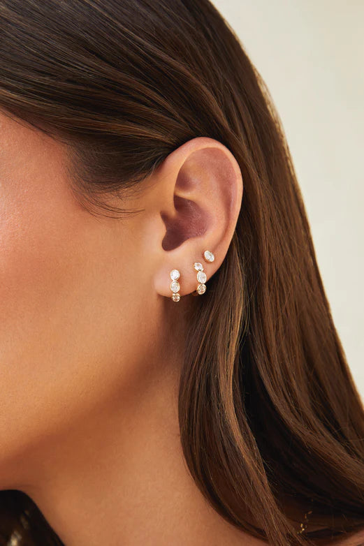 EF Collection Bezel Set Oval Diamond Huggie Earrings in yellow gold styled on models ear.