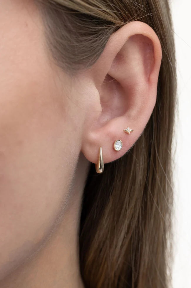 EF Collection Bezel Set Oval Diamond Stud Earrings in yellow gold styled on models ear.