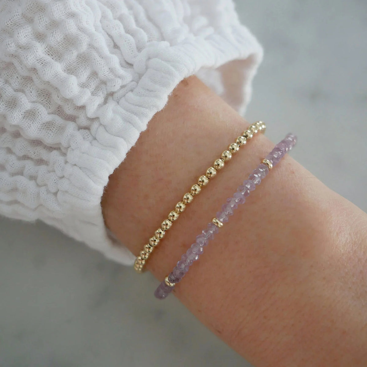 EF-Collection Birthstone Bead Bracelet In Amethyst in yellow gold styled on models wrist with gold bead bracelet