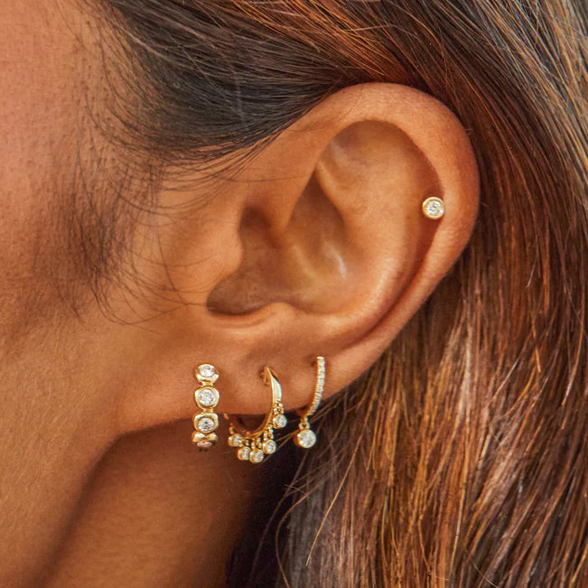 EF Collection Diamond Bezel Drop Mini Huggie Earring in yellow gold on models ear with diamond huggies.