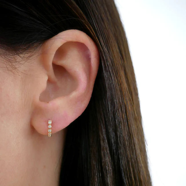 Single EF Collection Diamond Bezel Mini Huggie Earring in yellow gold on models ear.