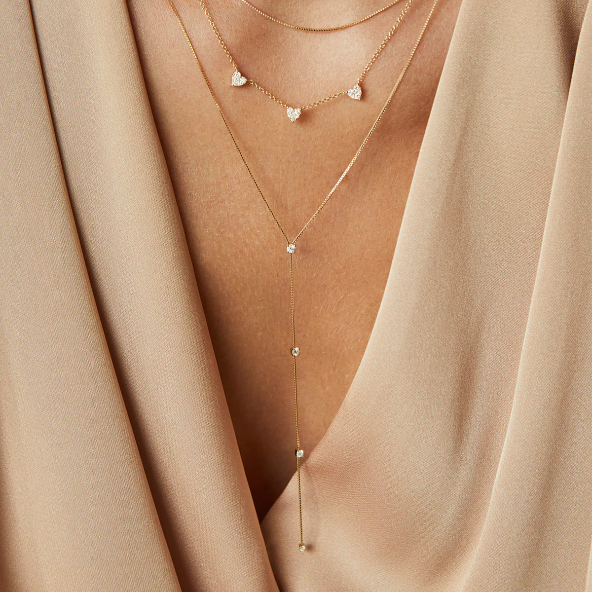EF-Collection Diamond Callae Lariat Necklace in yellow gold styled on models neck with diamond hearts necklace