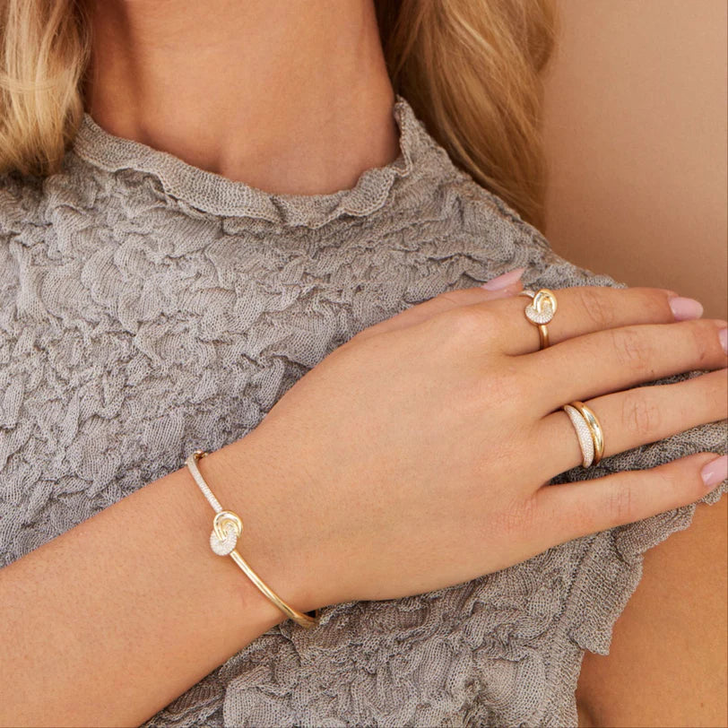 EF Collection Diamond & Gold Jumbo Love Knot Bangle Bracelet in yellow gold on models wrist with knot bangle ring on her finger.