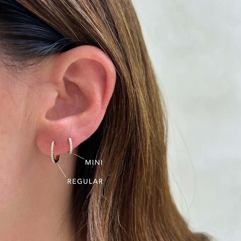 EF-Collection Diamond Mini Huggie Earrings in yellow gold on models ear comparing the sizes of the mini and regular huggies
