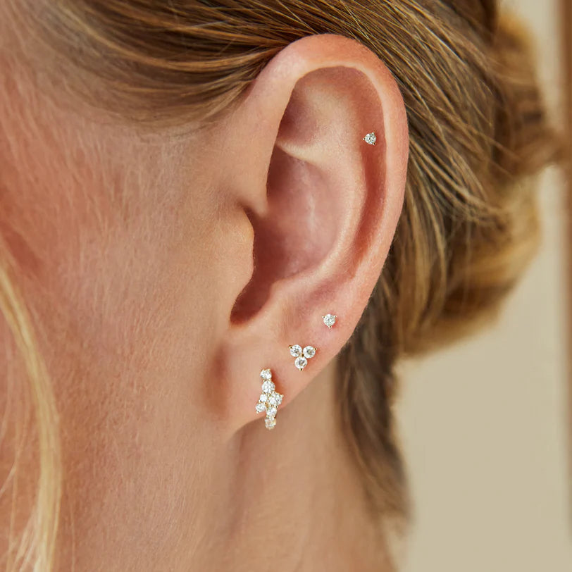 Close up of EF Collection Diamond Trio Stud Earring in yellow gold stacked on models ears with studs.