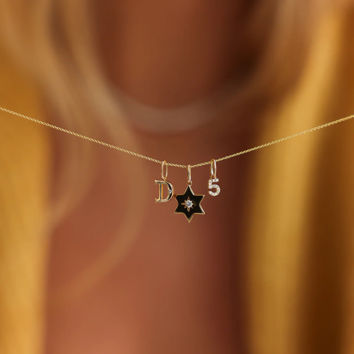 DRD Diamond Number Charm in yellow gold displayed with a star and an initial charm in a necklace.