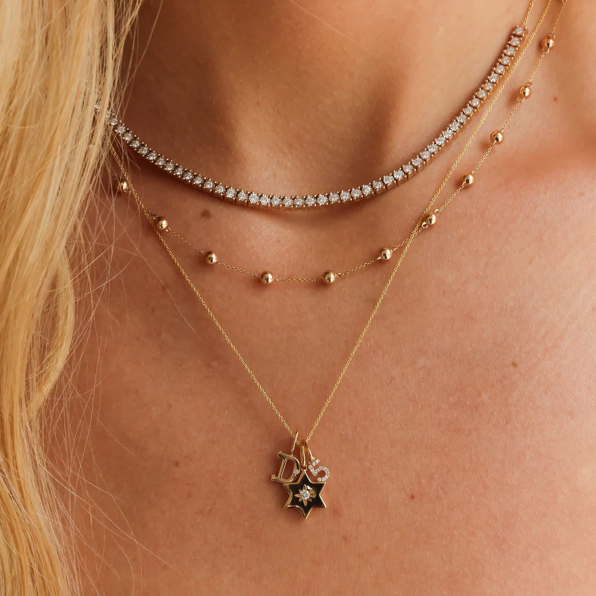 DRD Diamond Number Charm in yellow gold styled on models neck stacked with a tennis and a beaded necklace