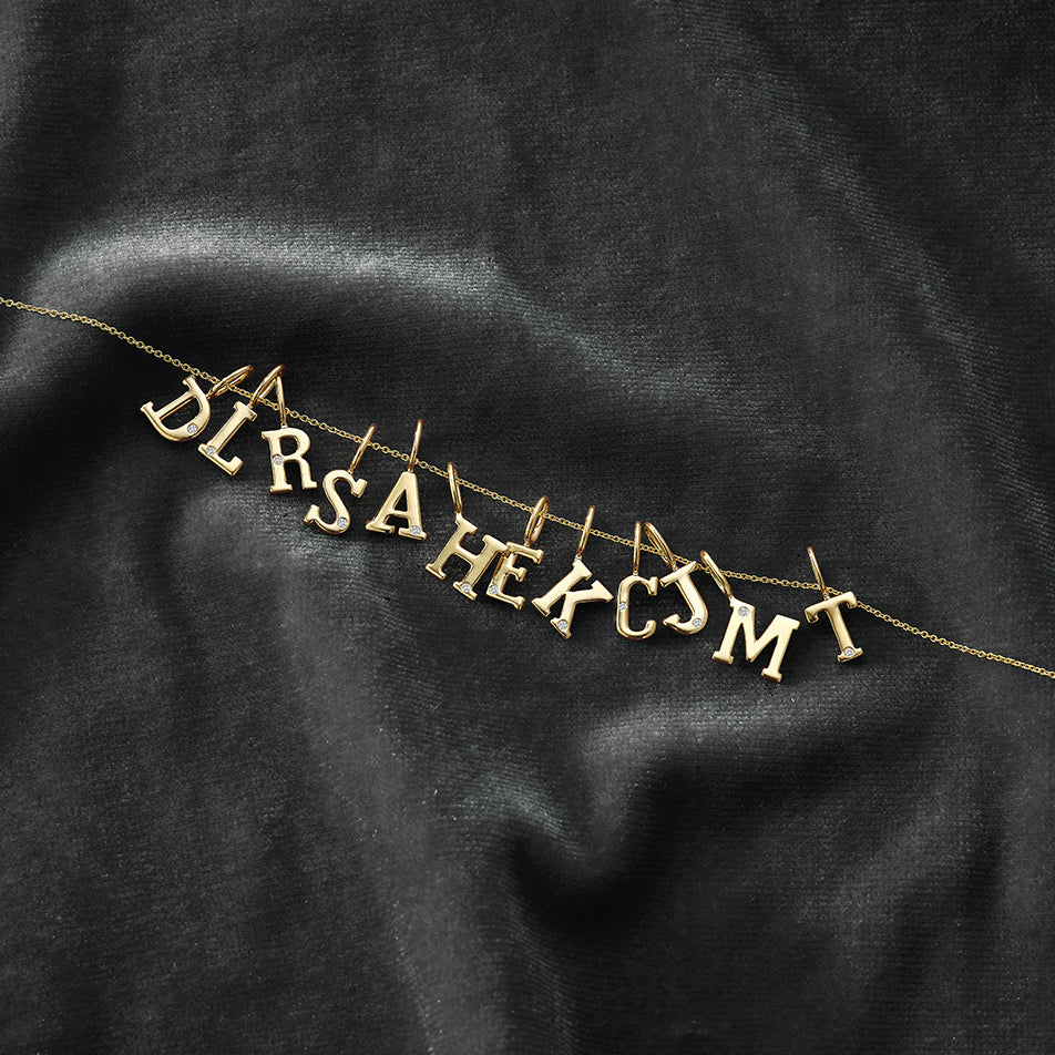 Dana Rebecca Designs DRD Gold Initial Charm in yellow gold on black background