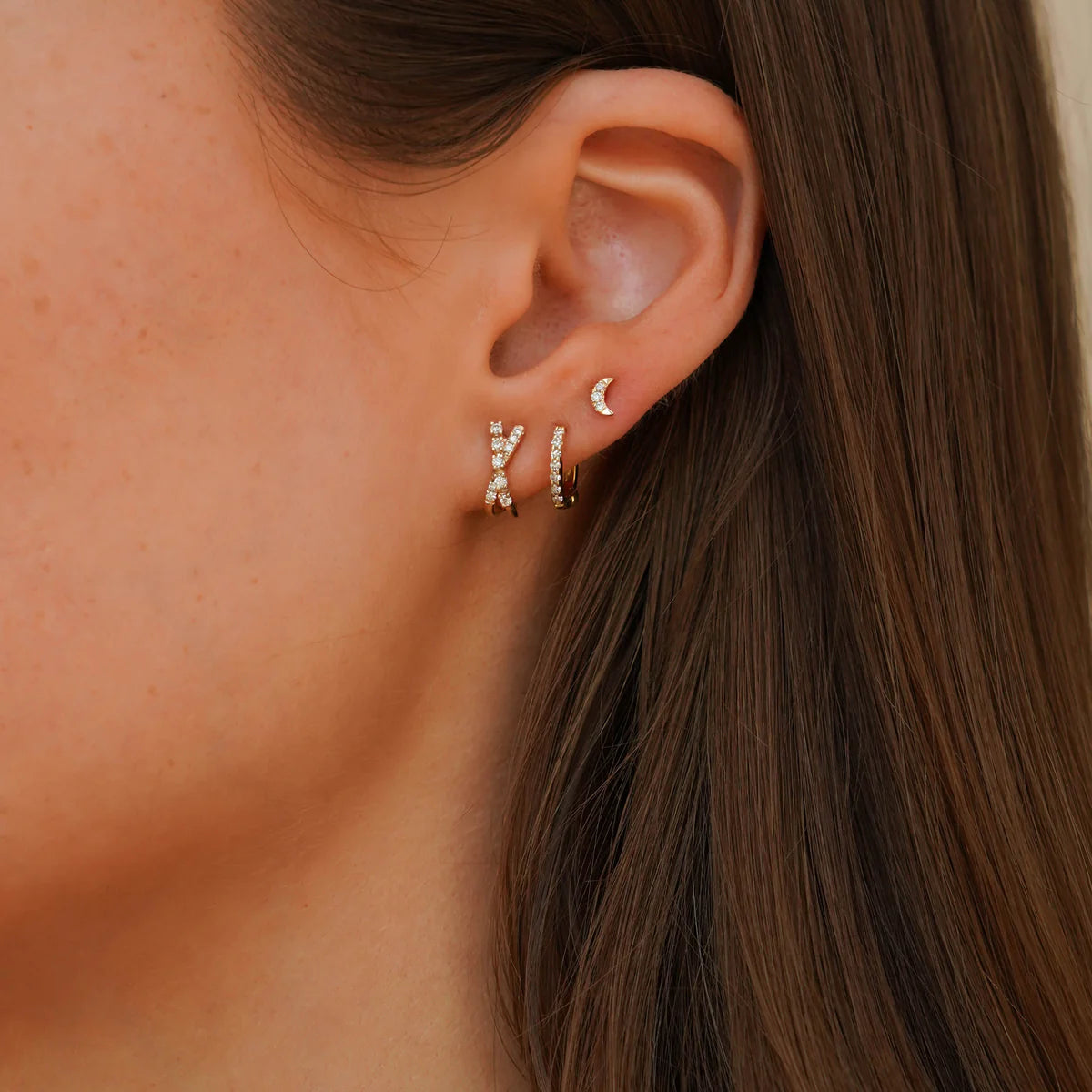 closeup of dana rebecca designs diamond mini huggie staked in an ear