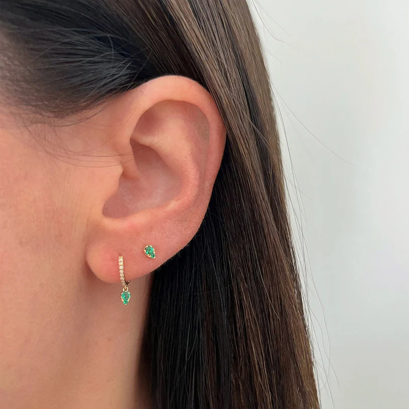 EF Collection Emerald Teardrop Diamond Mini Huggie Earring in yellow gold styled on models ear with a stud.