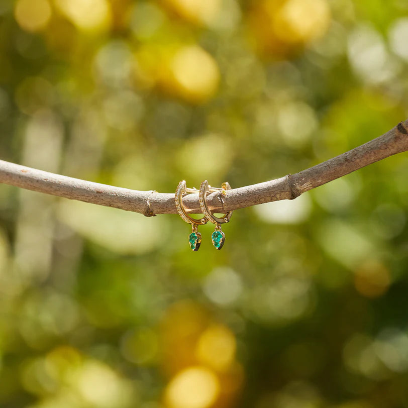 EF Collection Emerald Teardrop Diamond Mini Huggie Earring in yellow gold on a wooden stick