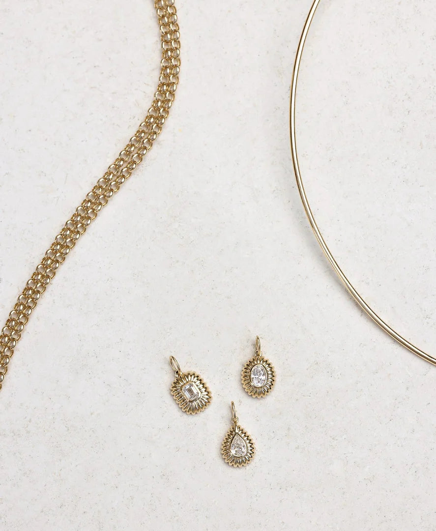 Three gold pendant with a central diamond on a white background