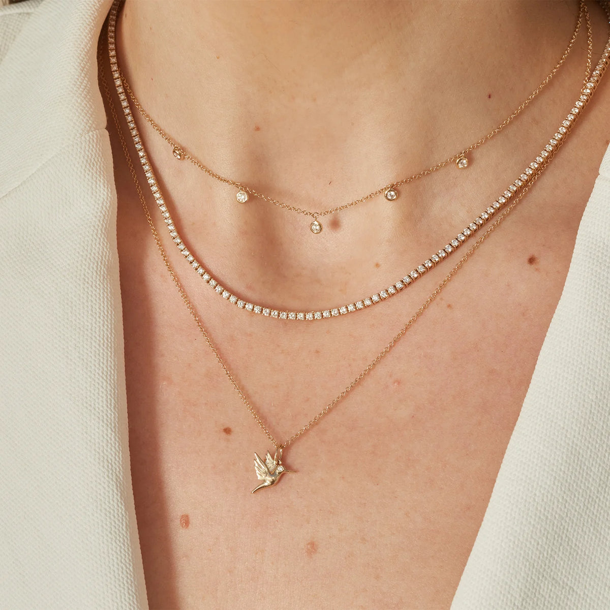 EF-Collection Gold Hummingbird Charm Necklace in yellow gold styled on models neck with diamond tennis necklace