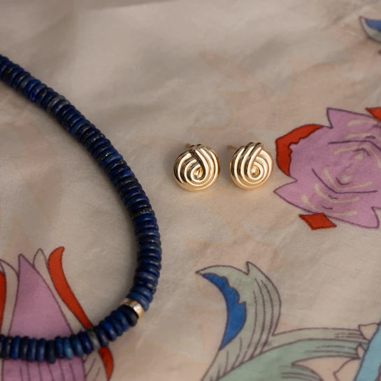 EF-Collection Gold Swirl Stud Earrings in yellow gold styled on a scarf with a floral design