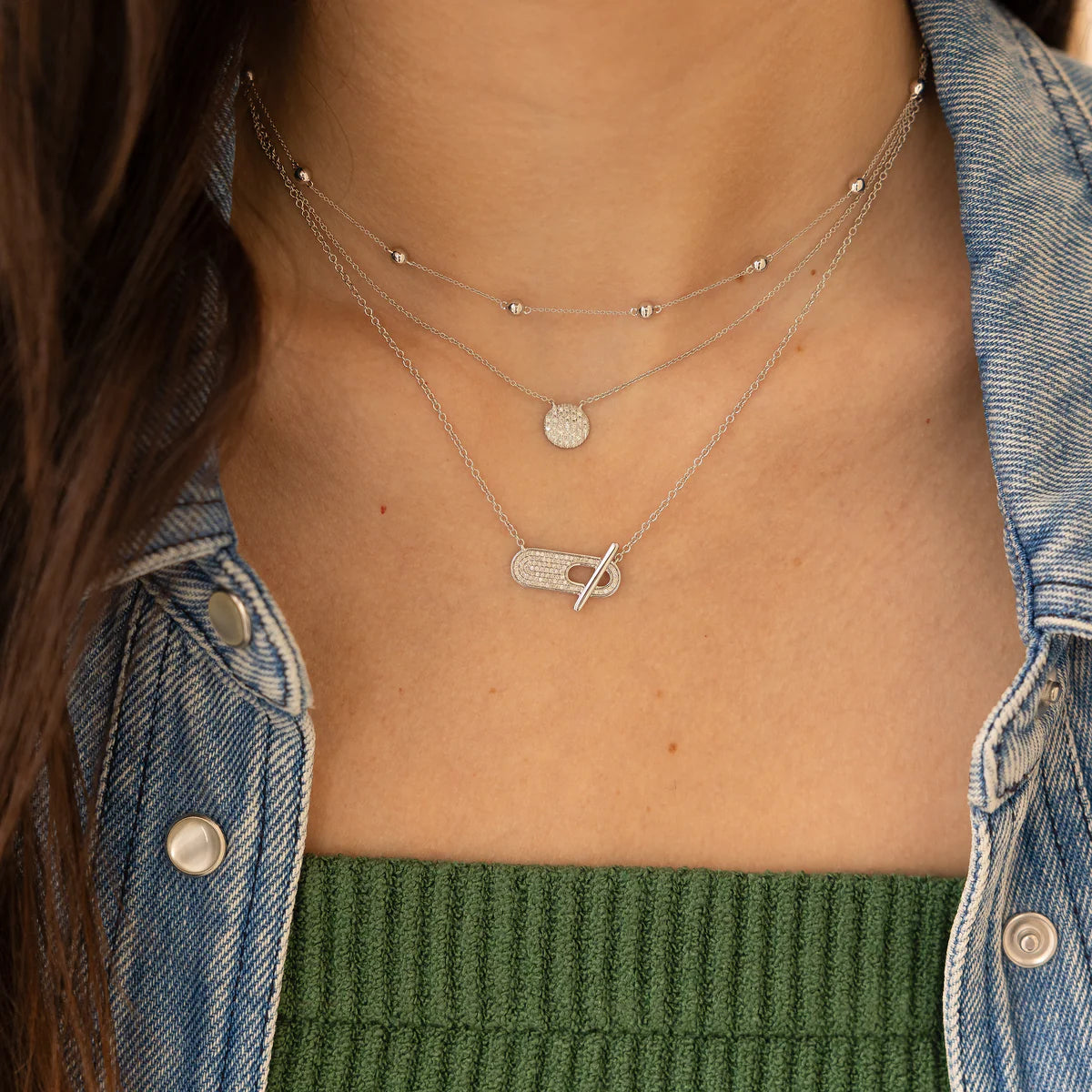 close up of Dana Rebecca Designs Lauren Joy Medium Disc Necklace in white Gold layered with other necklaces