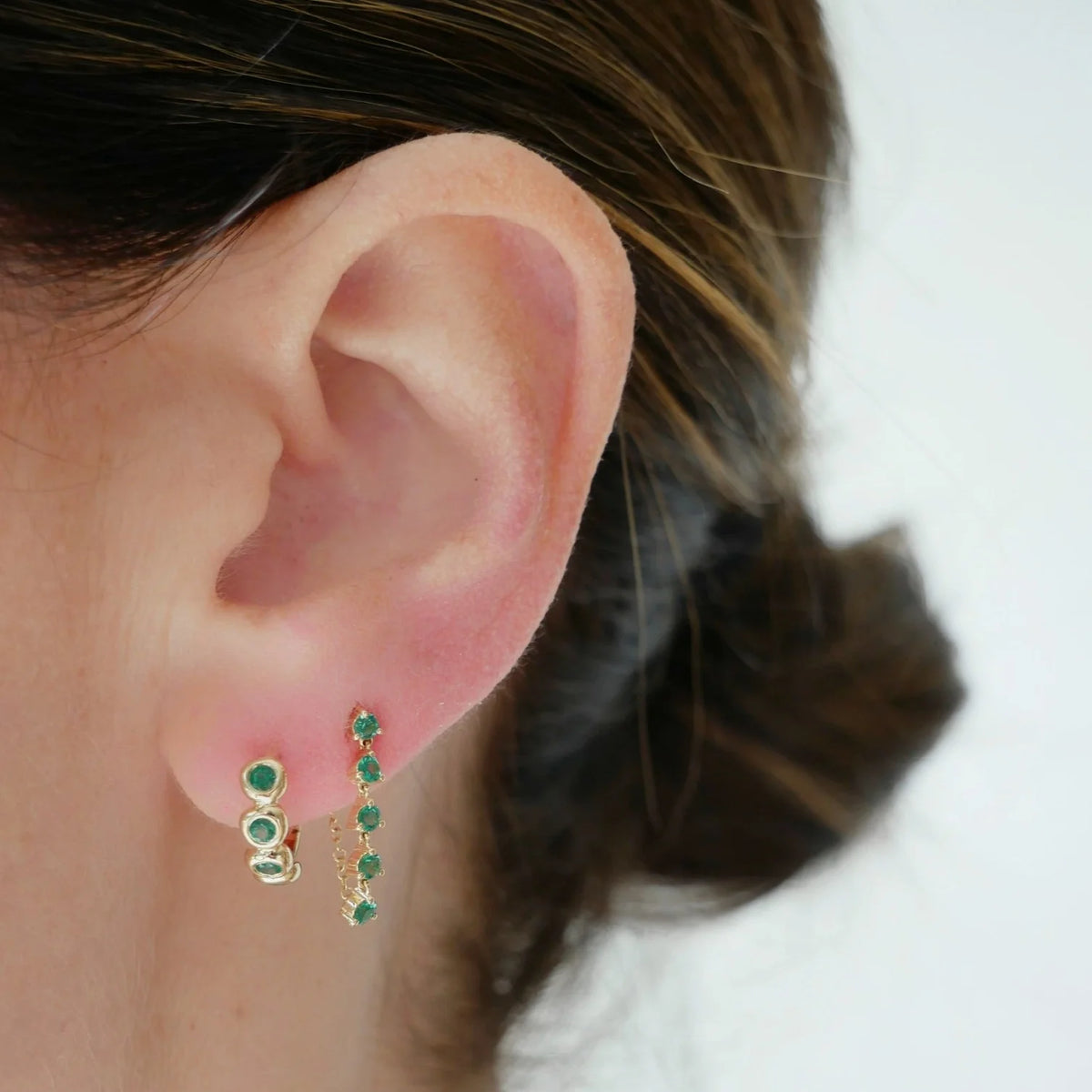 EF-Collection Multi Emerald Chain Stud Earrings in yellow gold styled on models ear with emerald huggie