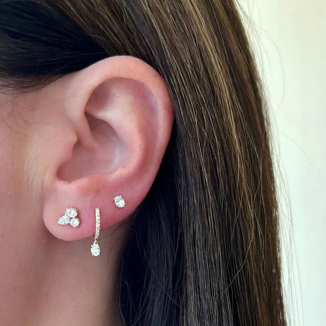EF Collection Oval Drop Diamond Mini Huggie Earring in yellow gold styled on models ear with studs.