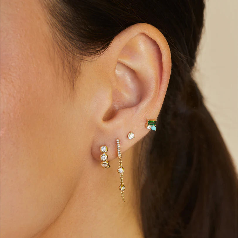 Pillow Chain Diamond Mini Huggie Earring in yellow gold on models ears stacked with a huggie and two piercings.