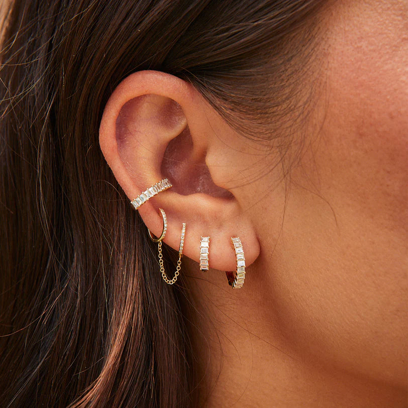 EF-Collection Prong Set Diamond Baguette Huggie Earrings in yellow gold on models ear stacked with diamond baguette cuff and chain huggies