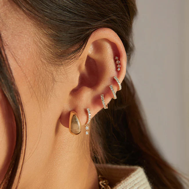 Close up of EF Collection Prong Set Diamond Double Drop Mini Huggie Earring in yellow gold models ear.