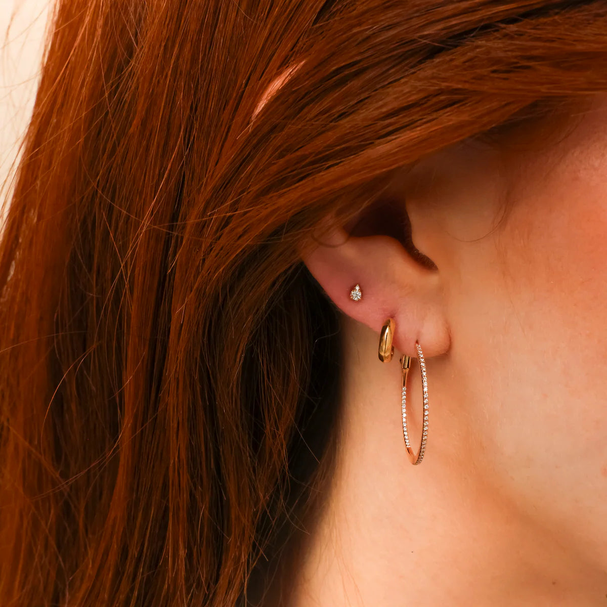 close up of Dana Rebecca Designs Sophia Ryan Petite Teardrop studs in rose gold on model's year and styled with hoops