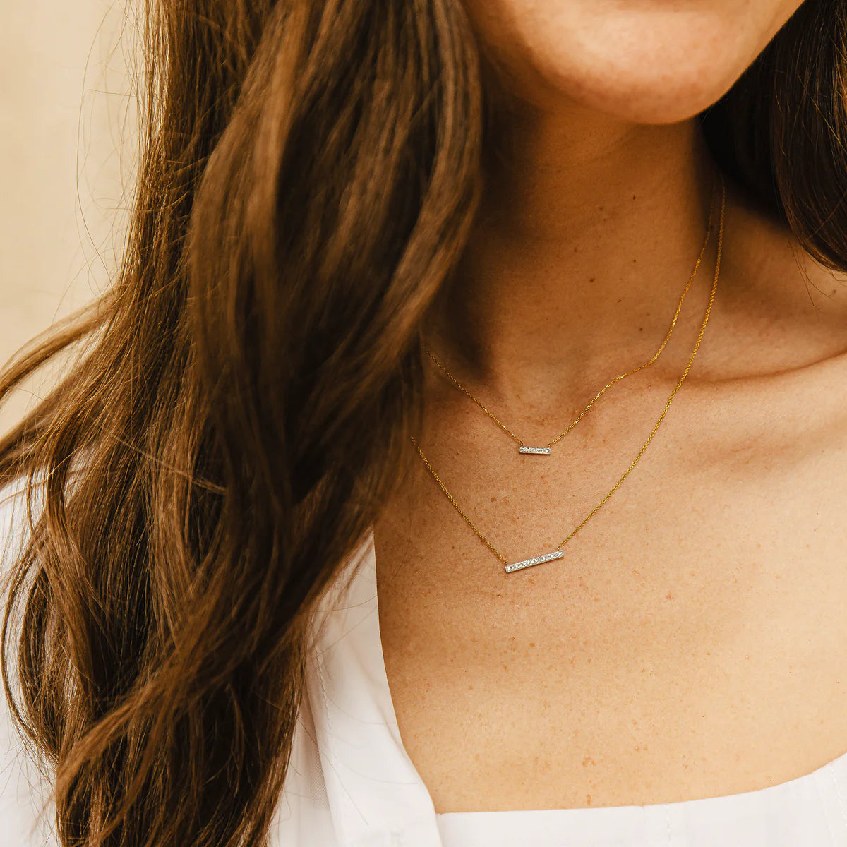 close up of Dana Rebecca Designs Diamond Sylvie Rose Bar Necklace with a yellow gold chain and diamonds layered with another necklace