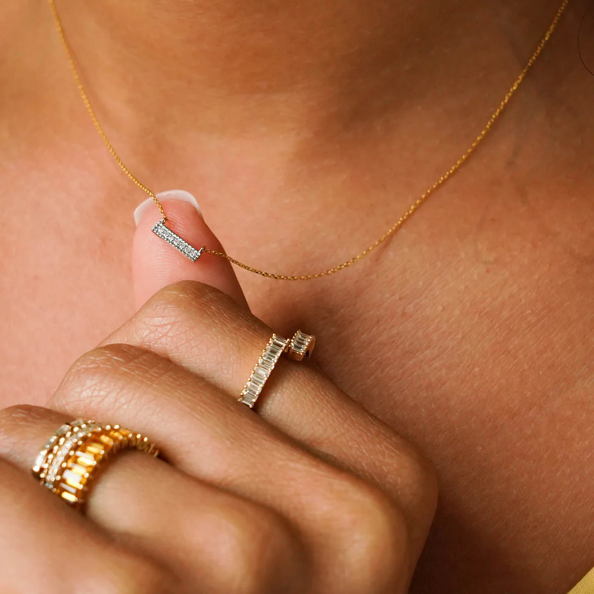 close up of Dana Rebecca Designs Diamond Sylvie Rose Bar Necklace with a yellow gold chain and diamonds on model's hand