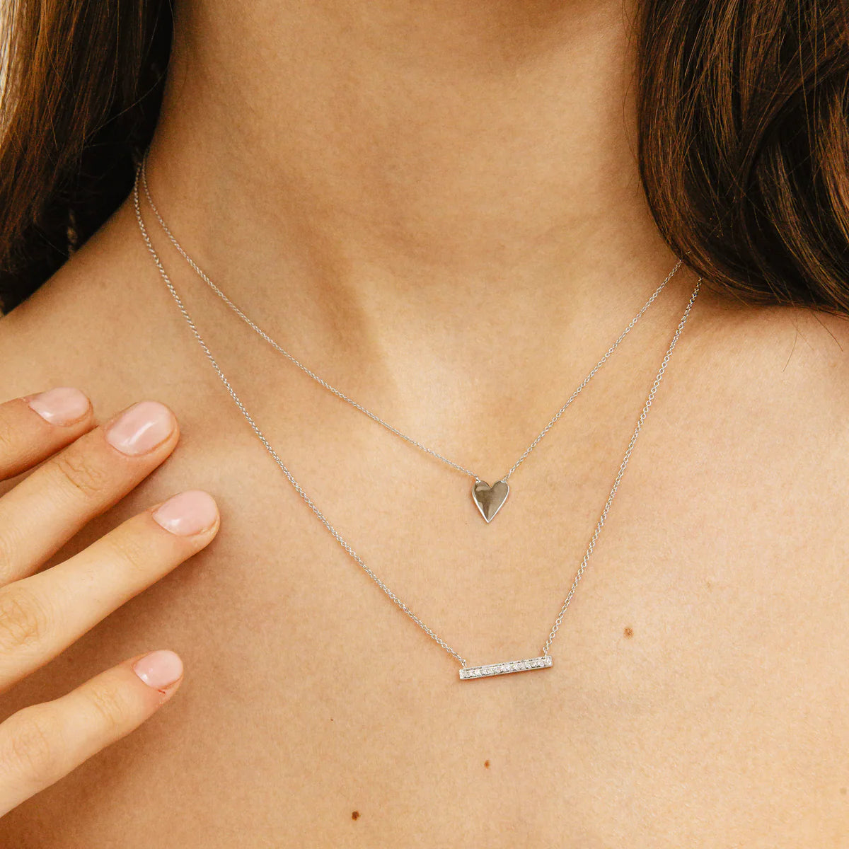 close up of sylvie Rose 14K white Gold Medium Bar Necklace layered with other necklaces