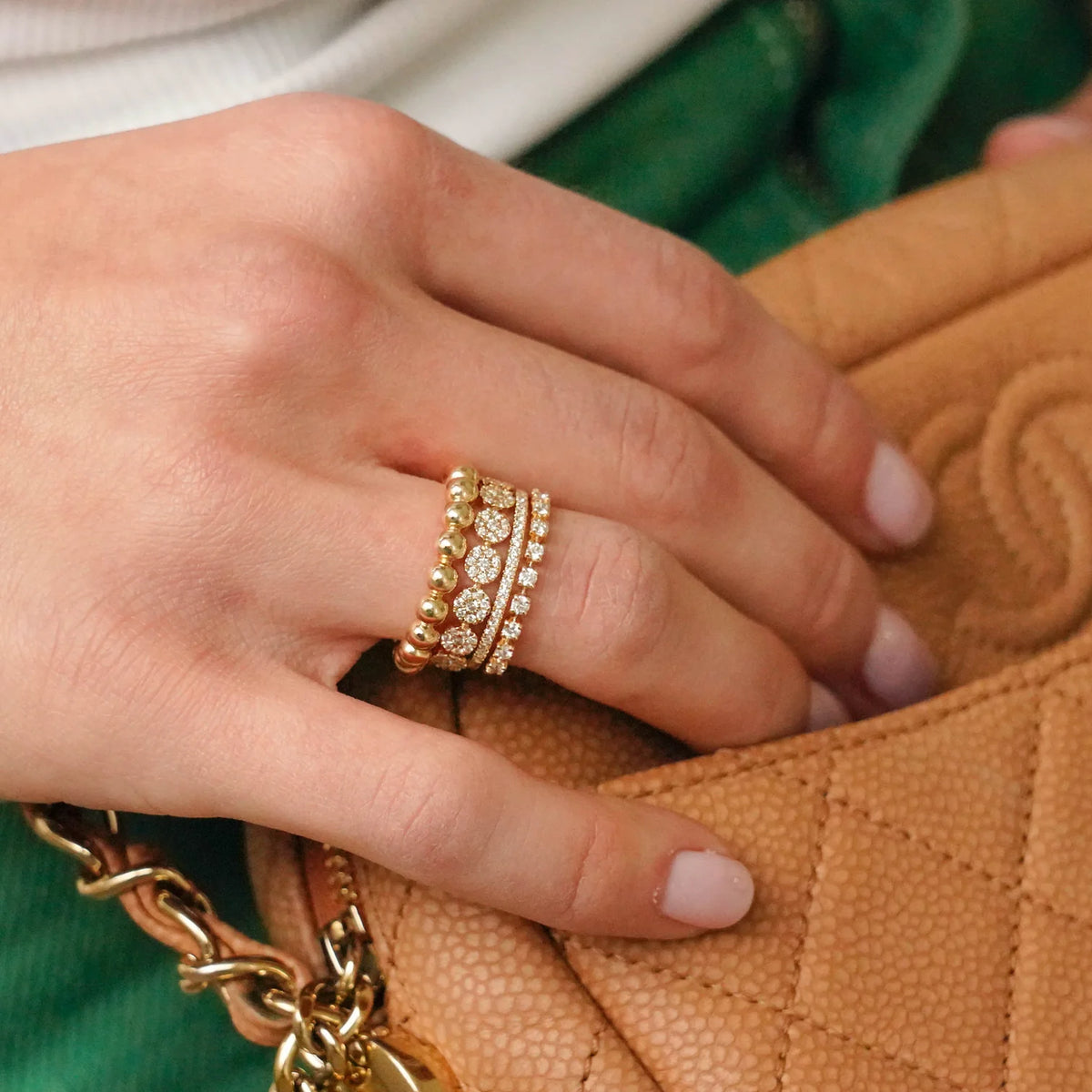 Dana Rebecca Designs Taylor Beth Eternity Band Ring in yellow gold stacked on models finger holding a channel bag