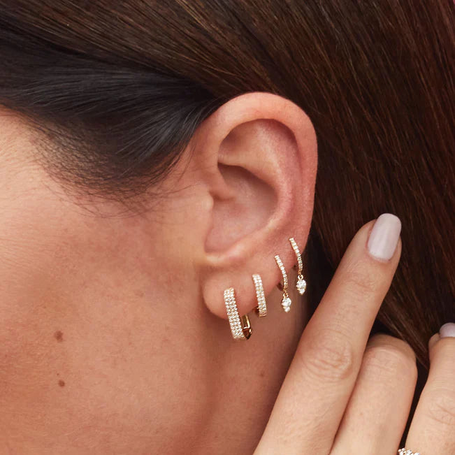 EF Collection Teardrop Diamond Mini Huggie Earring in yellow gold styled on models ears layered with diamond huggies.
