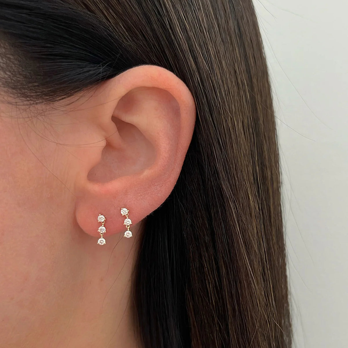 Pair of EF-Collection Triple Prong Set Diamond Stud Earrings in yellow gold styled on models ear