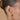 Close-up of an ear wearing Ef Collection Gold Knot Huggie earrings with a blurred background