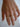 Hand wearing two gold rings on a light background