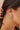 Close-up of a person wearing gold hoop earrings with a hand adjusting hair.