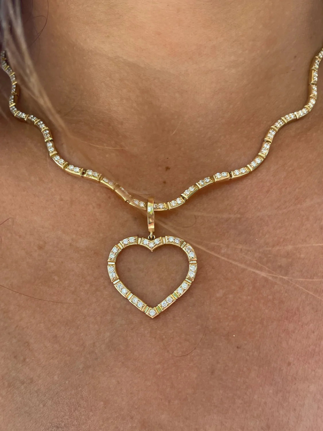 close up of Onirikka Glimmer Diamond Heart Charm in 18k yellow gold with pavé diamonds on wave necklace