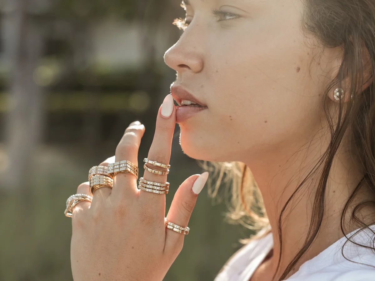 close up Shot of a model wearing Onirikka Oval Gold Ring in 18k yellow gold with a blurry background.