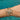 Wrist with multiple Onirikka gold bracelets against a blue glittery background.