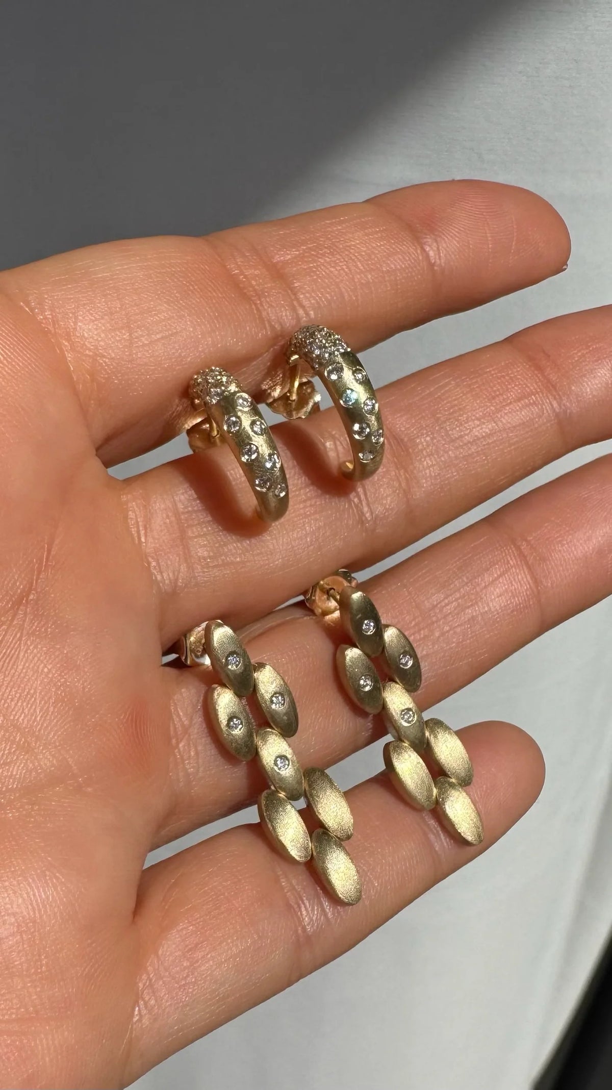 Close up of Onirikka Surf Rider Statement earrings in yellow gold on a hand.