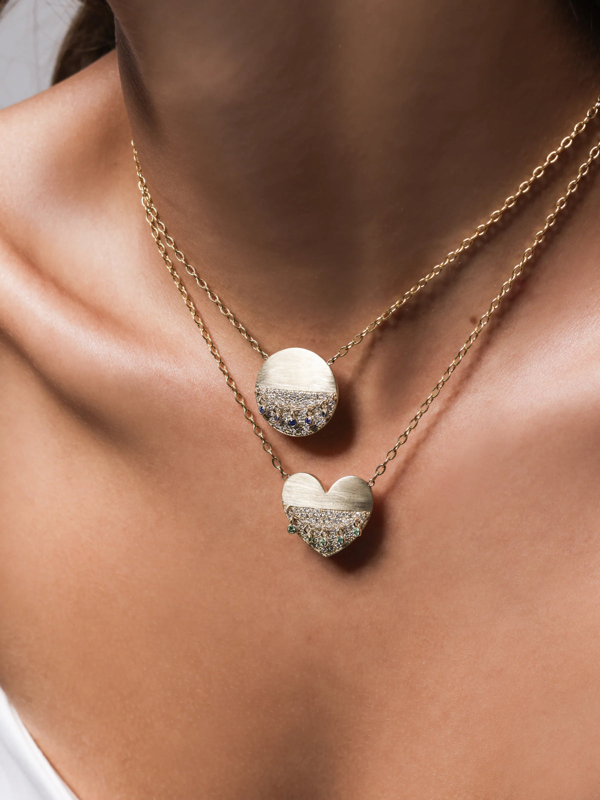 Close-up of a woman wearing Onirikka Round Hemline Medallion necklace in yellow gold with diamonds and blue sapphire