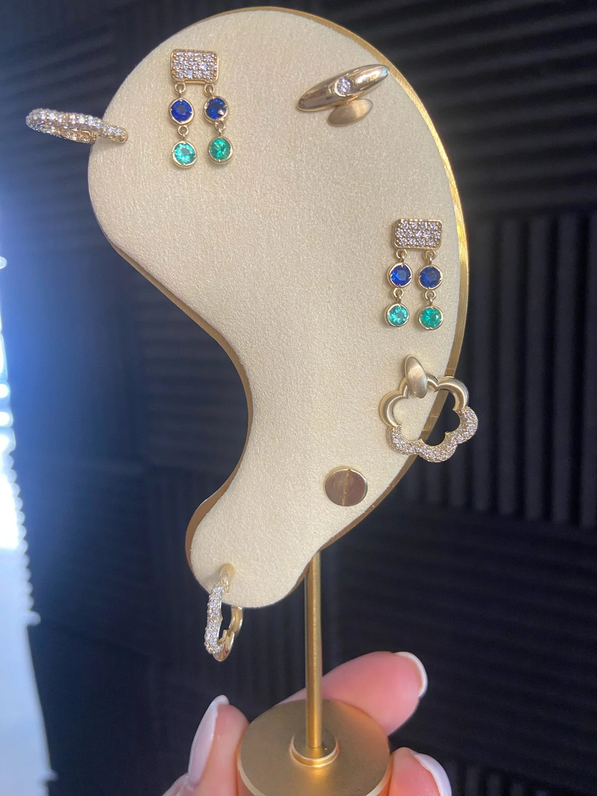 Product Shot of Onirikka Surf Rider Studs in yellow gold styled on a display with other earrings